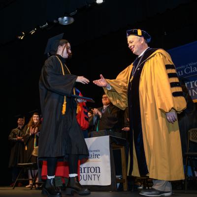 Chancellor Schmidt shaking graduate hand, Barron campus 