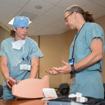 A student works on a simulation with a Mayo Clinic physician, both wearing scrubs.