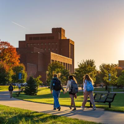 Students walk across campus as the fall sun sets.