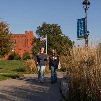 Two students walk across campus on a fall day