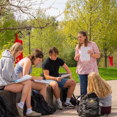 Students in a math class learn from a professor in an outdoor classroom area