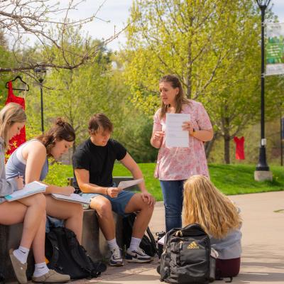 Students in a math class learn from a professor in an outdoor classroom area