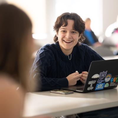 Student smiles at another student in a classroom