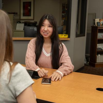 Student smiles at another student while sitting across from one another