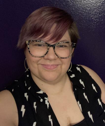 Hannah with short purple hair wearing a black shirt with white lightning bolts on a purple background