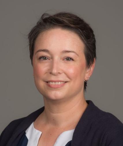 A picture of KT Gallagher. In it, she is smiling and has short dark hair.