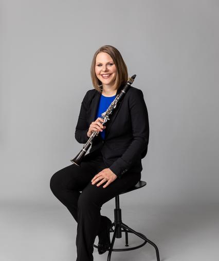 Dr. Alyssa Powell sitting on stool with clarinet.