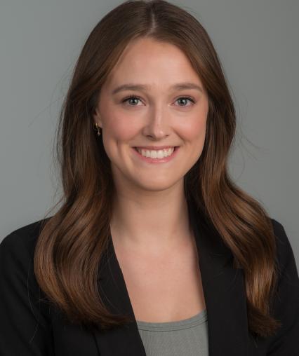 Professional Headshot of Lindsey Boehm. Long brown hair, blue eyes, green top, black blazer.