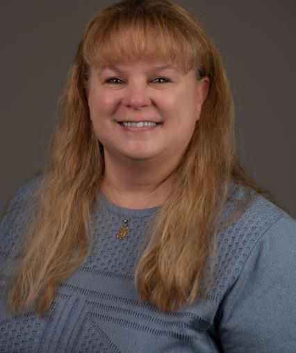 Headshot of woman with long hair wearing a blue blouse.