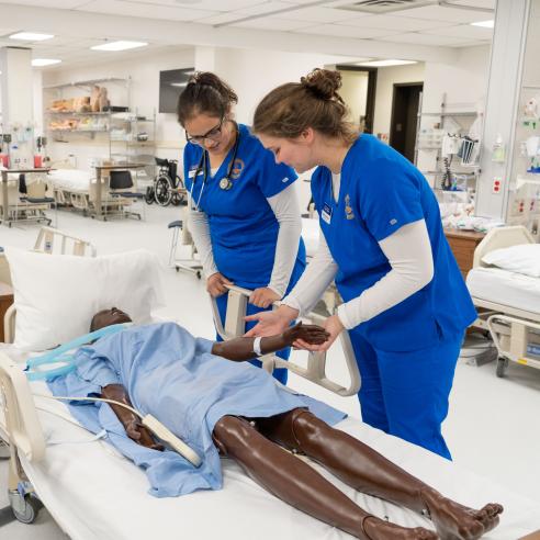 two students working in nursing SIM lab