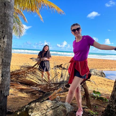 An image of 2 students doing social volunteer work in a sunny day at the beach