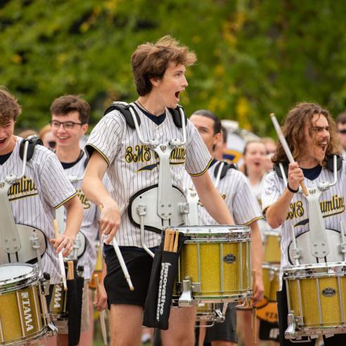 Energetic UWEC members of a drumline, dressed in striped jerseys