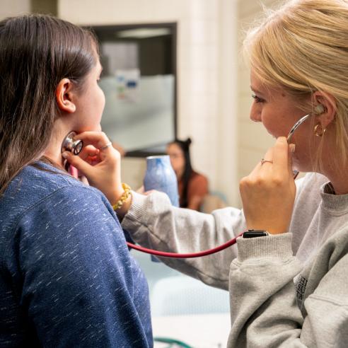 An image of two women in clinic, and using stethoscope to listen heartbeat