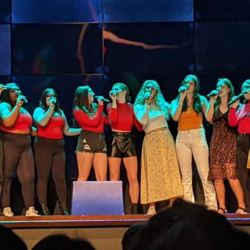 A group of The Callisto A Cappella student org singing on the stage