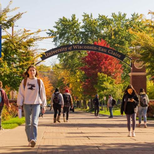 Students walking along UWEC pathway in autumn foliage