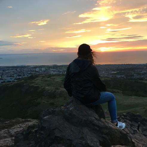A student on a study abroad program in Harlaxton, England, taking picture with a stunning sunset over a coastal cityscape