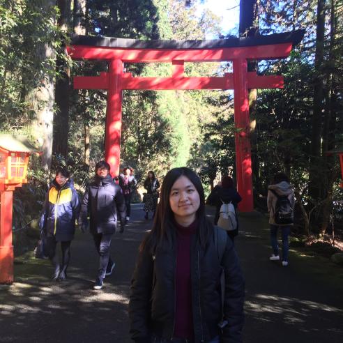 A student on a study abroad program in Hirakata, Japan standing in front of a traditional red torii gate