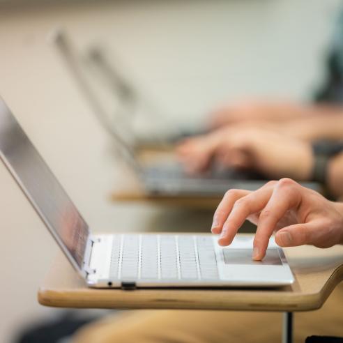 A picture of someone typing on a laptop