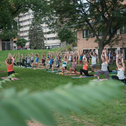 A group of people doing outdoor yoga behind Horan hall