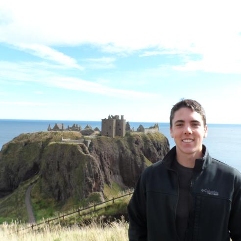 a picture of student during study aboard in Scotland in the foreground with the historic ruins of Dunnottar Castle