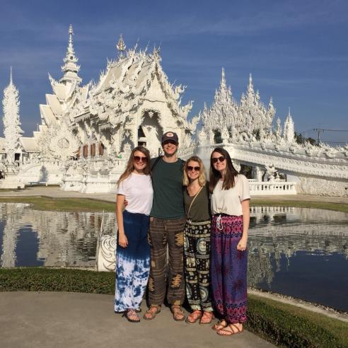 A group photo of students on a study aboard trip to Thailand posting in front of the white temple