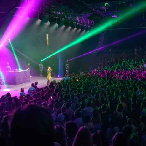A picture of concert scene with singer performing on the stage with energetic student crowd in Zone Arena Hall