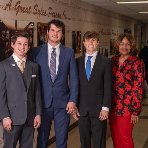 Professional photo of three sales team students with Dr. Lenita Davis outside of the UWEC Sales Center