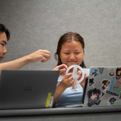 Two students using paper tools in a lecture hall.