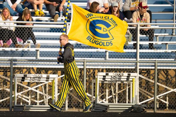 student walking with athletics flag at a track meet