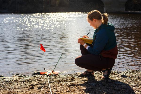 female student using geography instrumentation by the river bank