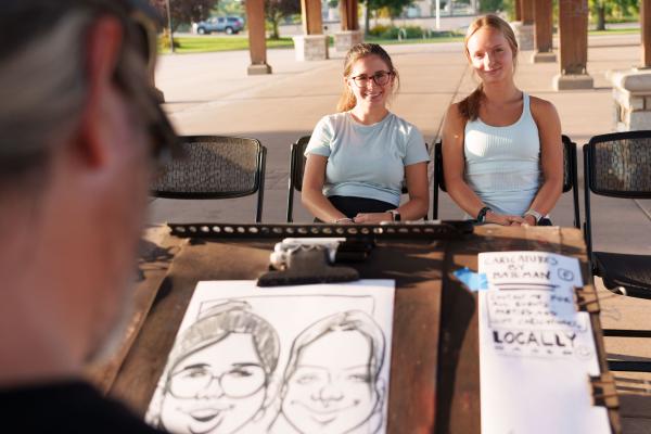 two students having caricature drawn at student event 
