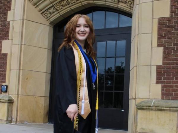 Graduate in cap and gown on Schofield steps 