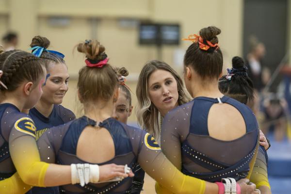 Coach Jessie DeZiel with Blugold gymnasts at a meet
