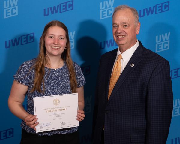 Chancellor posed with student at award ceremony, she is holding a scholarship certificate 