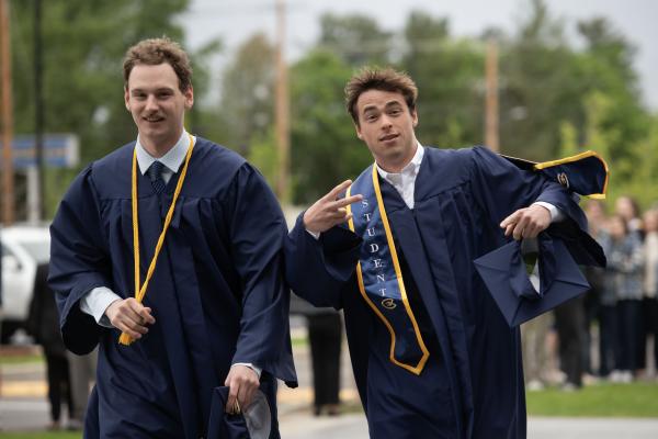 Two friends smiling after ceremony, peace fingers 