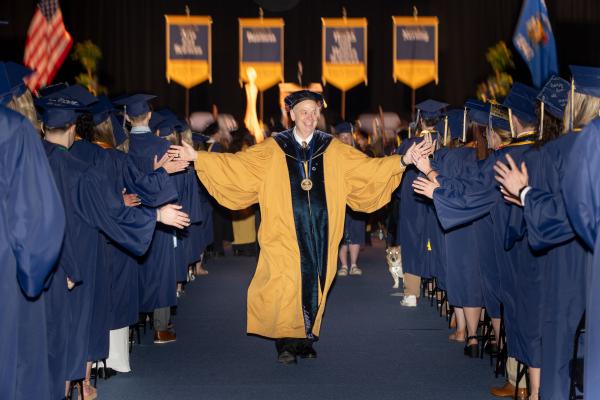 Chancellor high fives to graduates he passes exiting the arena