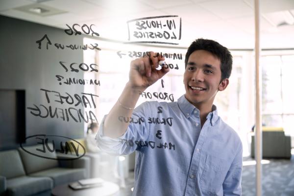 A student writes on a see-through board.