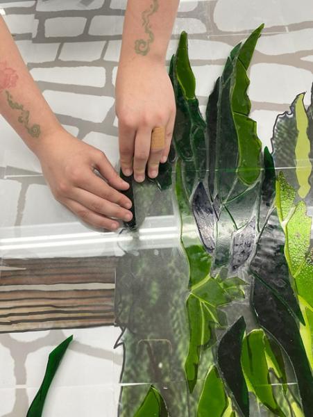 hands working on green leaves of glass panel