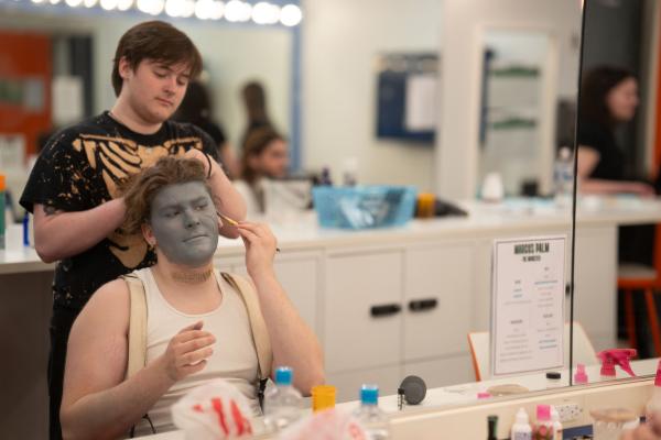 Student playing Frankenstein's monster getting makeup done before show 