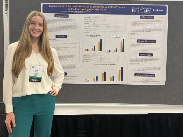 UWEC student Maren Durand stands to the left of her NASP 2025 conference poster