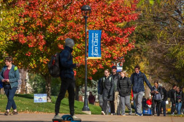 student passing scene fall colors, one student on hoverboard 