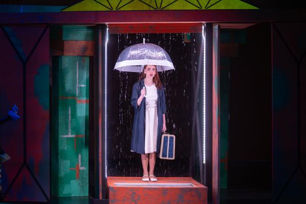 Woman with clear umbrella in an elevator holding a suitcase 