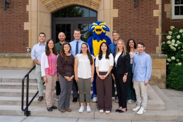 New Instructors standing with Blu the mascot on steps of building