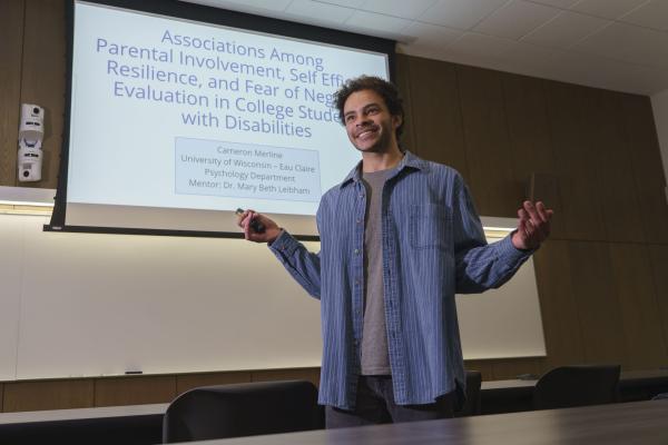 student presenting research in large classroom with white board