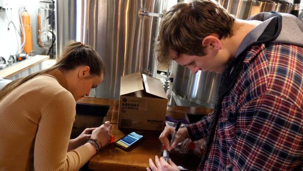 two students in local brewery labeling beer samples for testing