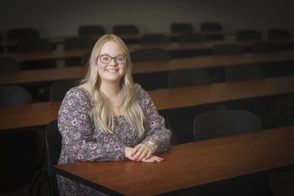 Grace Olson, female NCUR research student sitting at a desk, long blond hair, smiling.