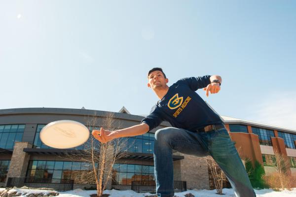male student in Blugold long sleeve t playing frisbee
