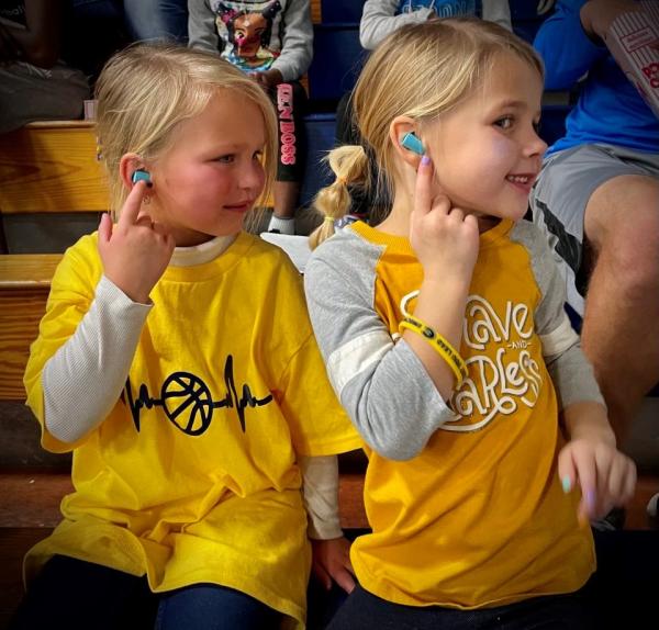young girls at a Blugold basketball game testing ear plugs