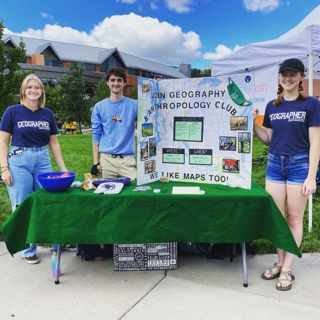 students in Geography club t-shirts at a table event outdoors