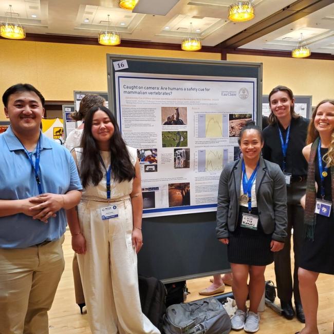 Group of student researchers smiling at poster presentation